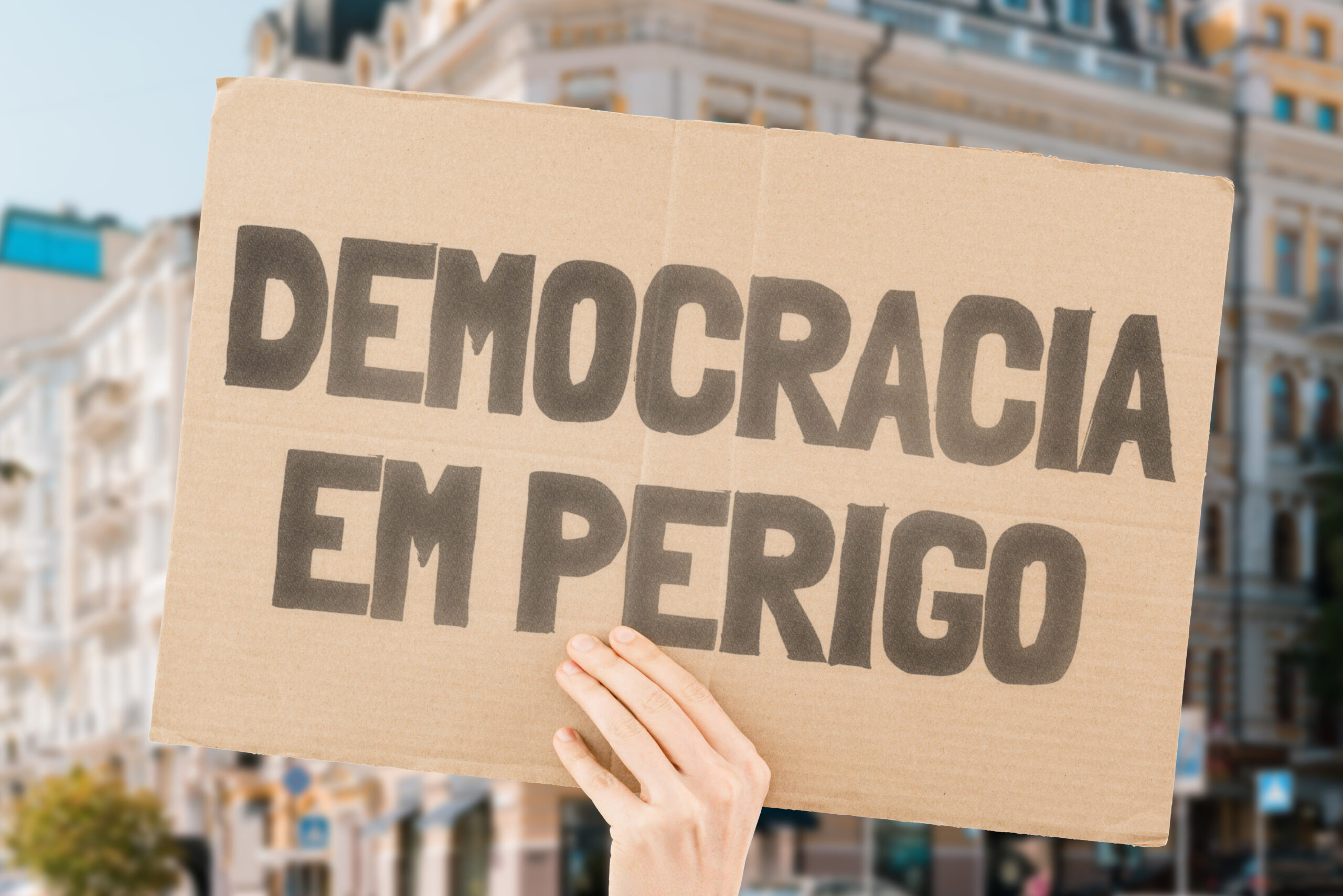 phrase-democracy-danger-is-banner-men-s-hands-with-blurred-background-politics-problem-solution-protest-political-crisis-collapse-crush